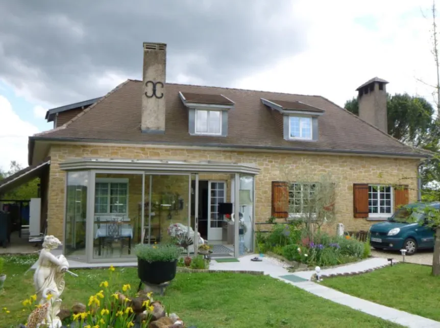Maison en pierre avec véranda et jardin fleuri